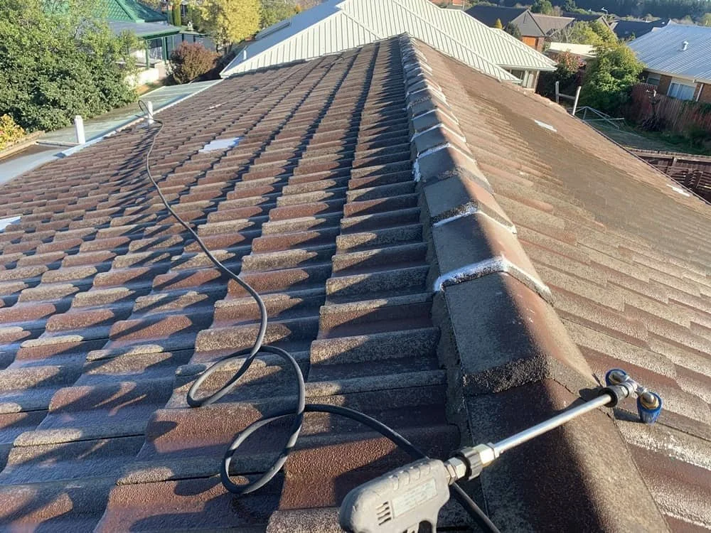 Tile roof being prepared and painted with rope and harness